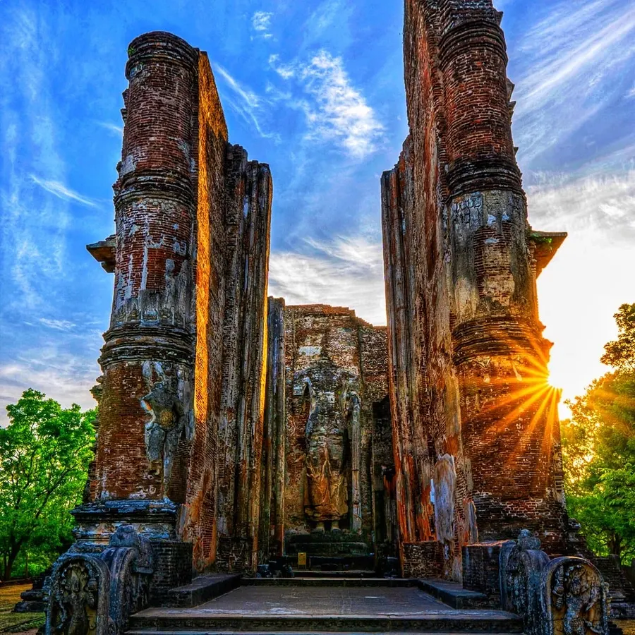 The ancient ruins of Lankatilaka Vihara in Polonnaruwa, Sri Lanka, featuring tall brick walls framing a large Buddha statue.