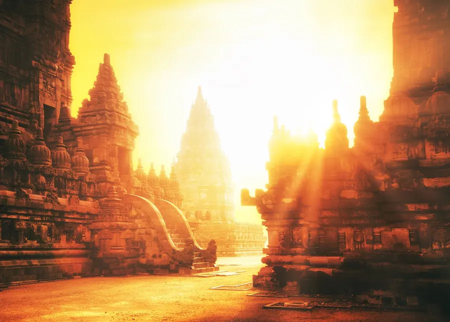 Sunlight flaring between ancient temple towers in Yogyakarta.
