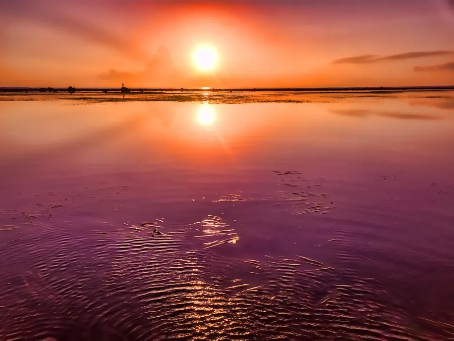 A low sun reflected across rippled shallow water.