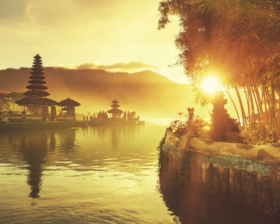 Ulun Danu Beratan Temple in Bali, Indonesia, illuminated by the golden light of sunrise.
