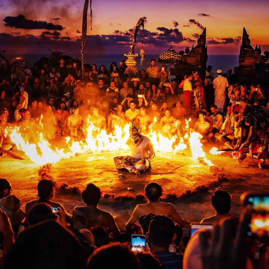 A Kecak Fire Dance performance at Uluwatu Temple in Bali, featuring a dancer sitting in the center of a fiery circle.